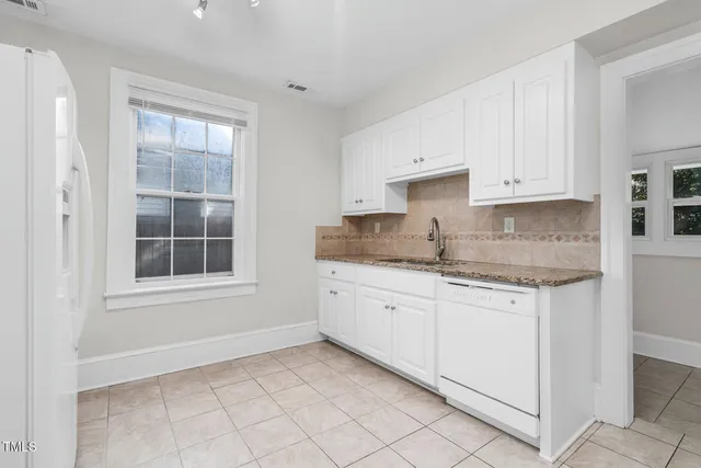 a kitchen with granite countertop white cabinets and a window