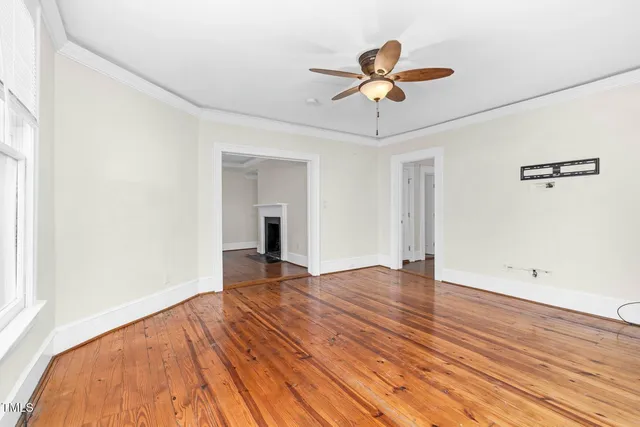a view of empty room with wooden floor and ceiling fan