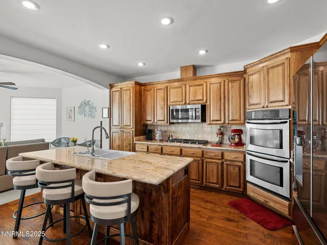 a kitchen with stainless steel appliances granite countertop a kitchen island hardwood floor sink stove dining table and chairs