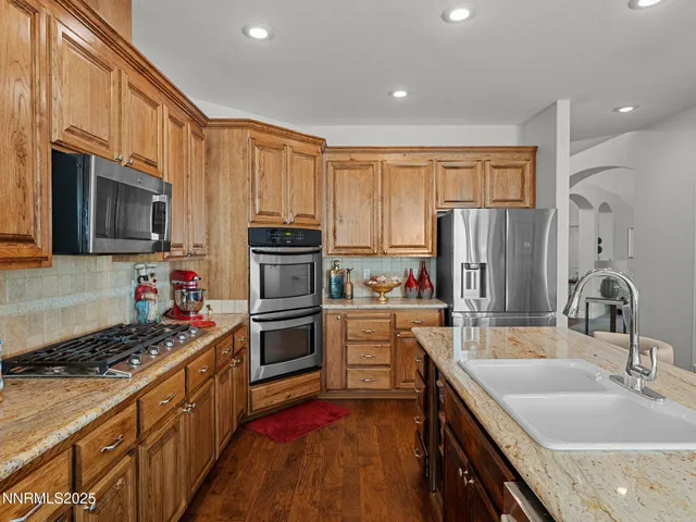 a kitchen with kitchen island granite countertop a sink stainless steel appliances and cabinets
