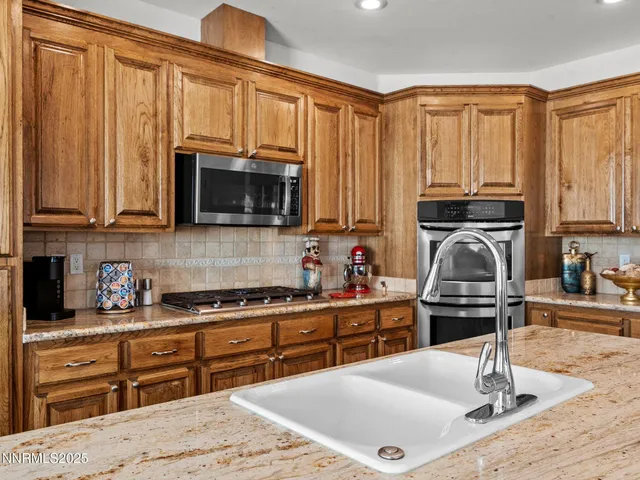 a kitchen with kitchen island granite countertop a stove top oven a sink dishwasher and wooden cabinets with wooden floor