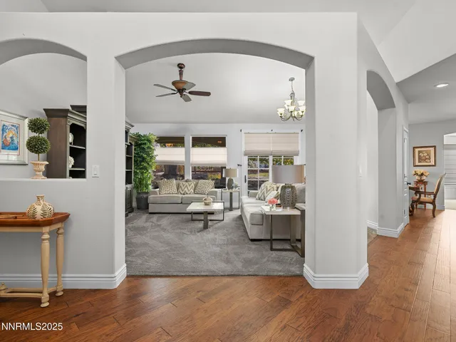 a living room with couches and kitchen view with wooden floor