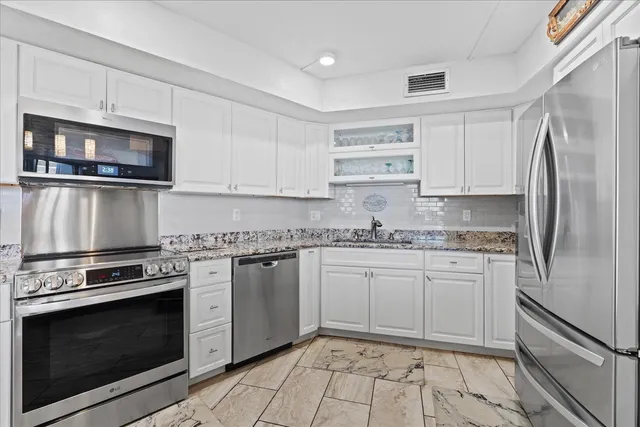 a kitchen with granite countertop a stove sink and refrigerator