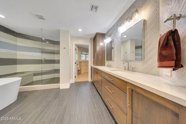 a spacious bathroom with a double vanity sink a mirror and a shower