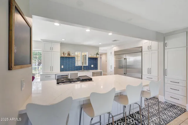 a kitchen with stainless steel appliances kitchen island granite countertop a refrigerator a stove a sink dishwasher with a dining table and chairs
