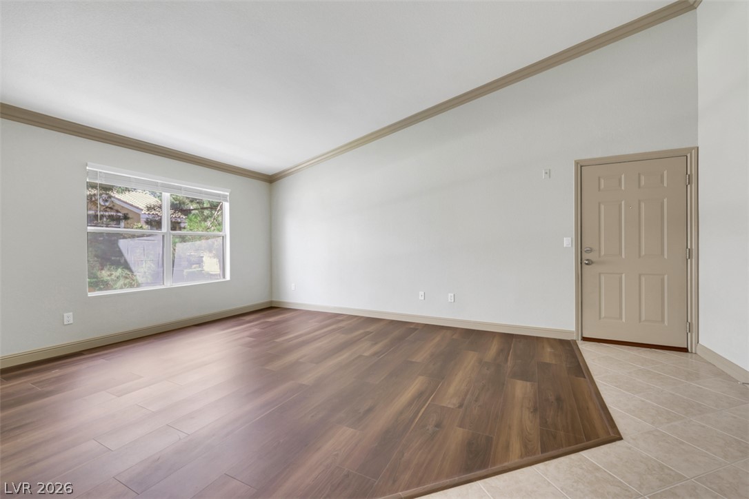 8101 West Flamingo Road, Unit 2136 Las Vegas, NV 89147 - Photo 6 of 32 Rich wood-look flooring meets tiled entry space under high vaulted ceilings and detailed crown molding.