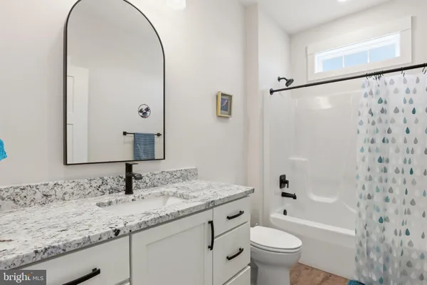 a bathroom with a granite countertop sink a toilet and shower