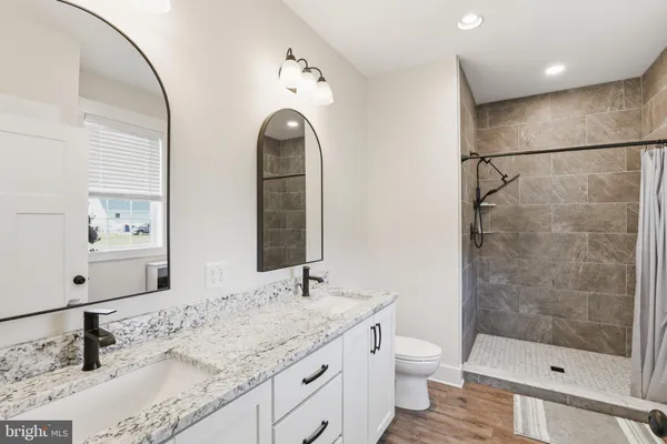 a bathroom with a granite countertop sink a toilet and shower