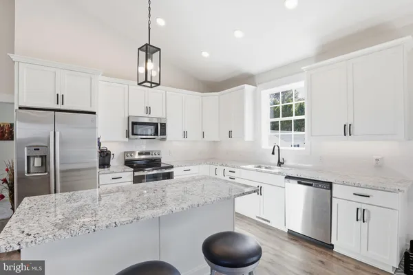 a kitchen with stainless steel appliances granite countertop a sink a stove a refrigerator cabinets and chairs