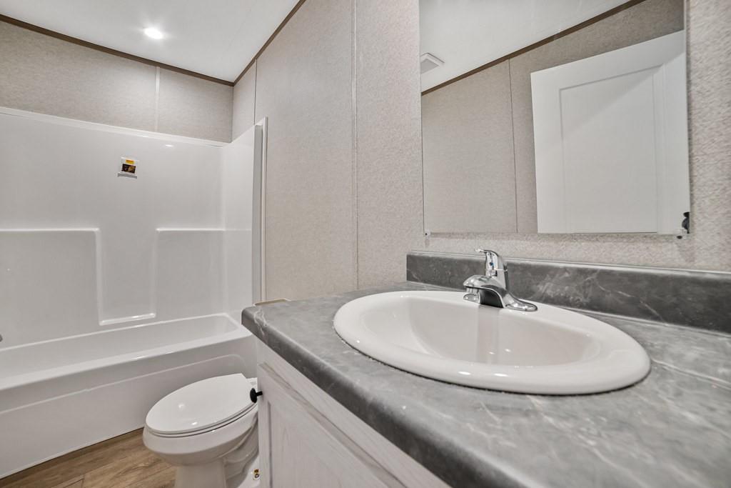 3106 Smyrna Road Sunset, TX 76270 - Photo 30 of 38 a bathroom with a granite countertop sink a toilet and a bathtub
