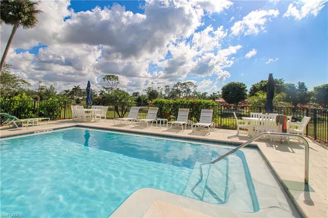 a view of swimming pool with seating area and trees in the background