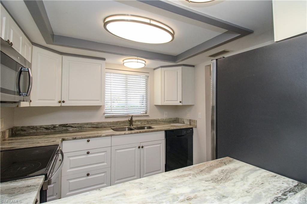 5635 Rattlesnake Hammock Road, Unit 102D Naples, FL 34113 - Photo 31 of 47 a kitchen with stainless steel appliances granite countertop a stove a sink and a microwave