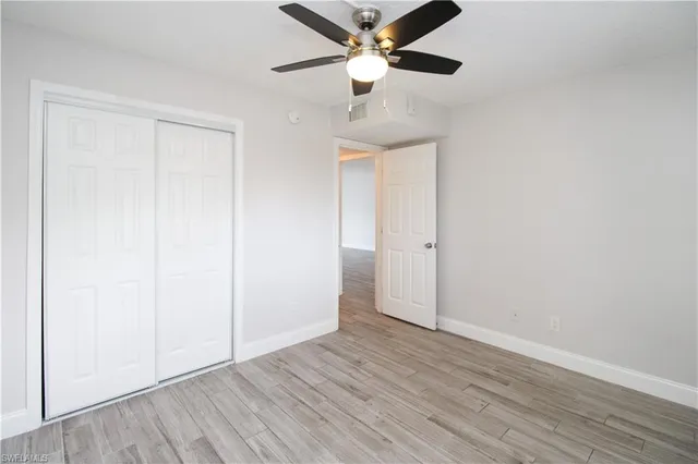 an empty room with wooden floor ceiling fan and window