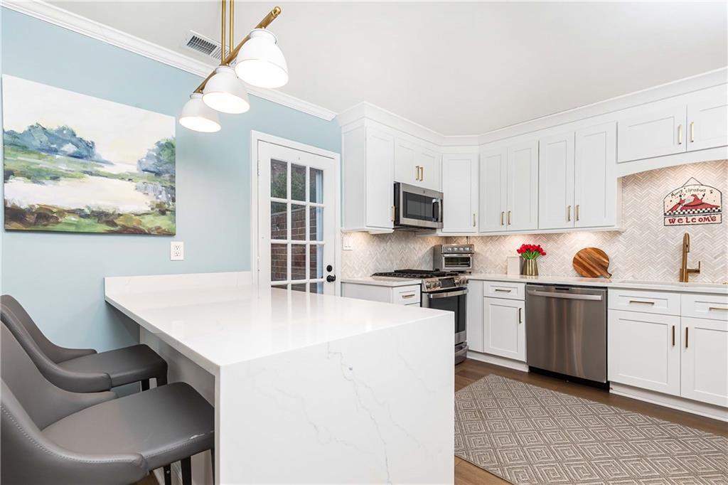 5 Middle Plantation Road Northwest, Unit 5 Atlanta, GA 30318 - Photo 11 of 33 a kitchen with stainless steel appliances a stove a sink a kitchen island and chairs in it