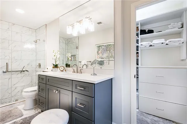 a bathroom with a sink a toilet a mirror and shower