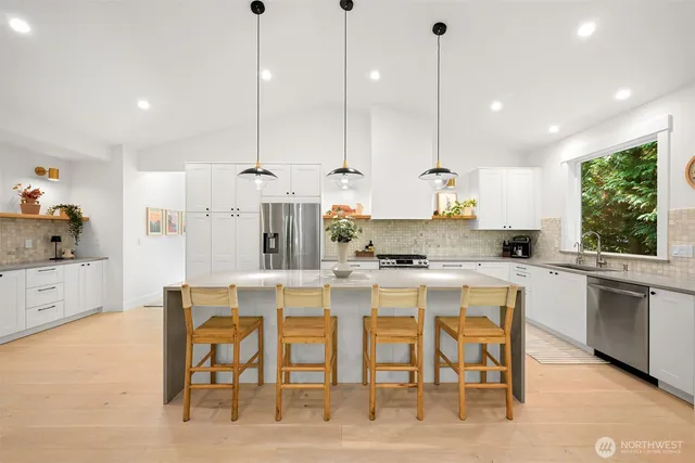 a kitchen with kitchen island a dining table chairs sink and cabinets