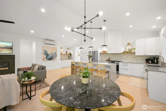 a living room with stainless steel appliances furniture a dining table and kitchen view