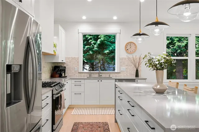 a kitchen with stainless steel appliances granite countertop a refrigerator a sink dishwasher a stove a dining table and chairs with wooden floor