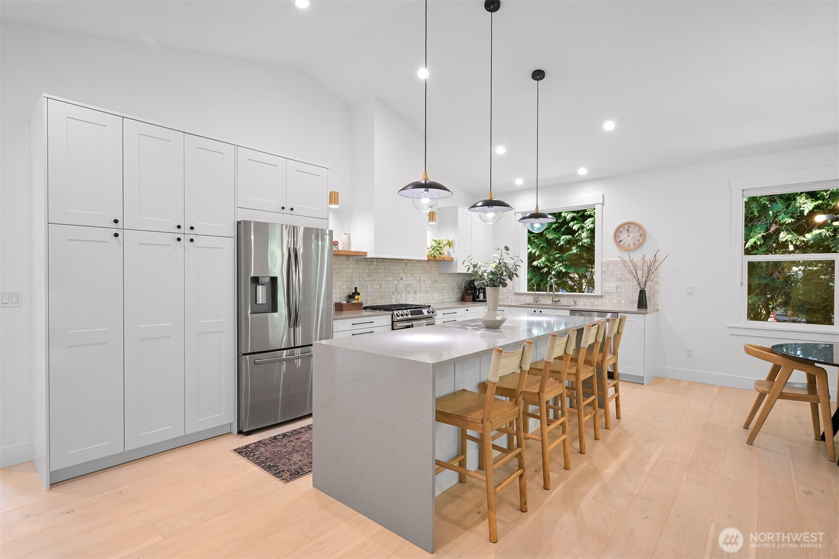5440 Tanager Road Blaine, WA 98230 - Photo 6 of 40 a kitchen with kitchen island a stove a refrigerator a dining table and chairs with wooden floor