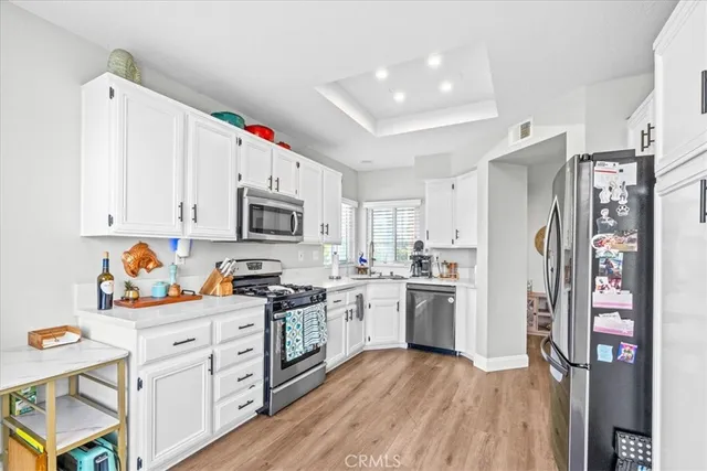 a kitchen with stainless steel appliances white cabinets and wooden floor