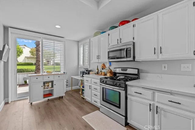a kitchen with stainless steel appliances white cabinets and a stove top oven