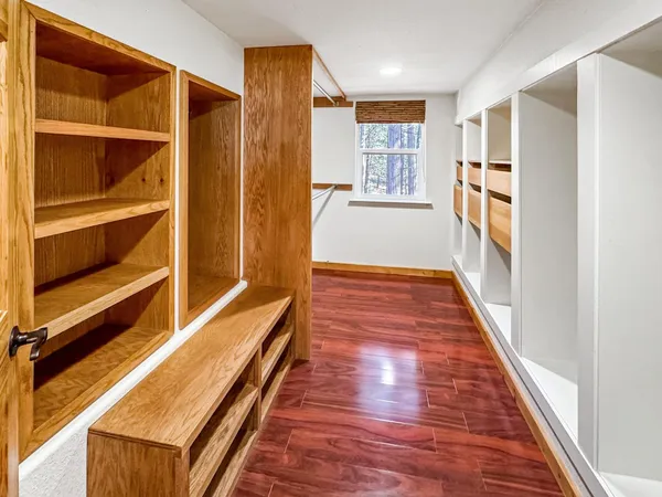 a hallway with wooden floor closet and windows