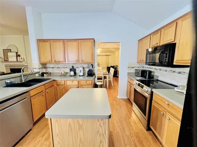 a kitchen with stainless steel appliances a stove a sink a microwave and cabinets
