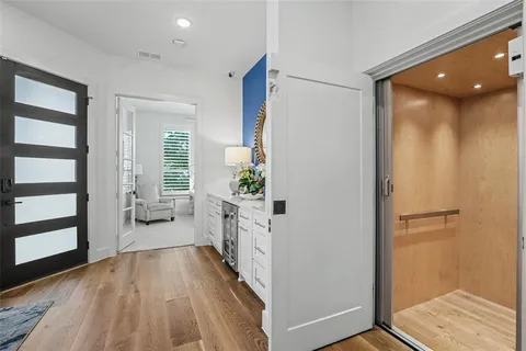 a view of a hallway to a livingroom with wooden floor and furniture