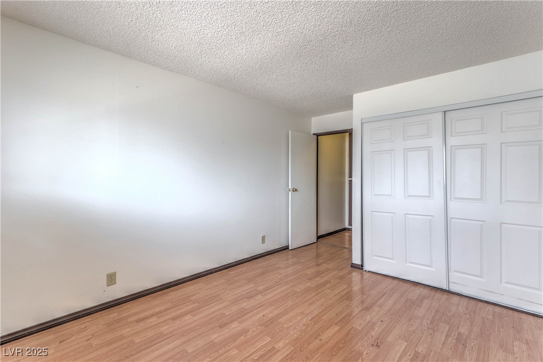 5404 South Swenson Street, Unit 34 Las Vegas, NV 89119 - Photo 12 of 28 Unfurnished bedroom featuring light wood-type flooring, a textured ceiling, and a closet