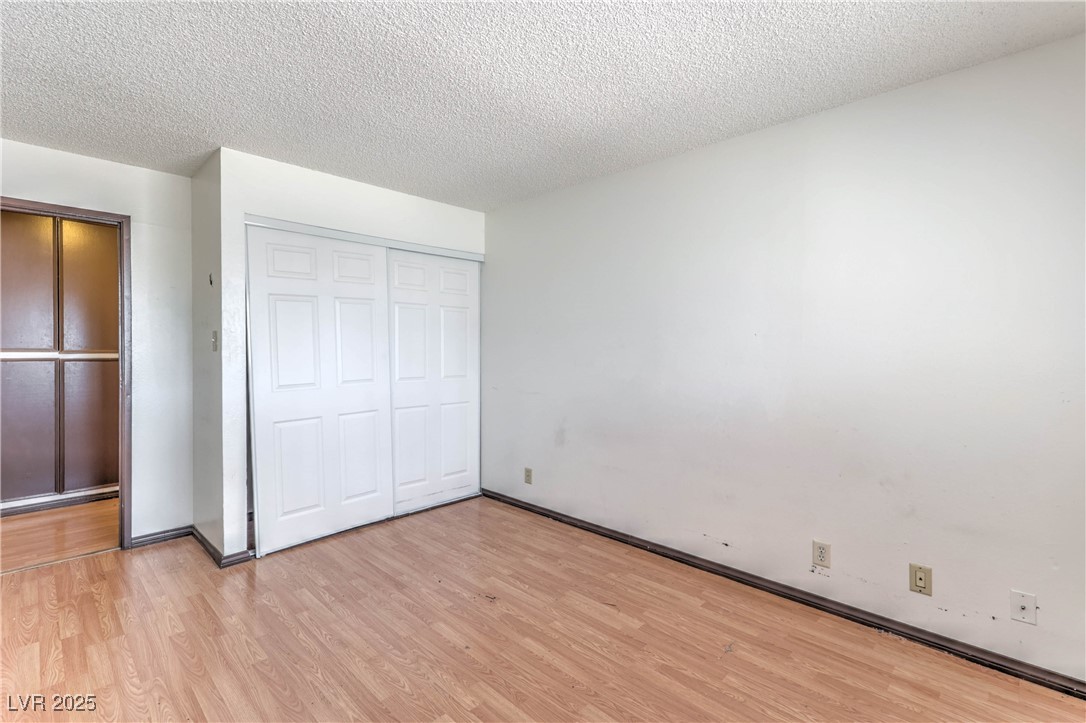 5404 South Swenson Street, Unit 34 Las Vegas, NV 89119 - Photo 13 of 28 Unfurnished bedroom featuring light wood-style floors, a textured ceiling, and a closet