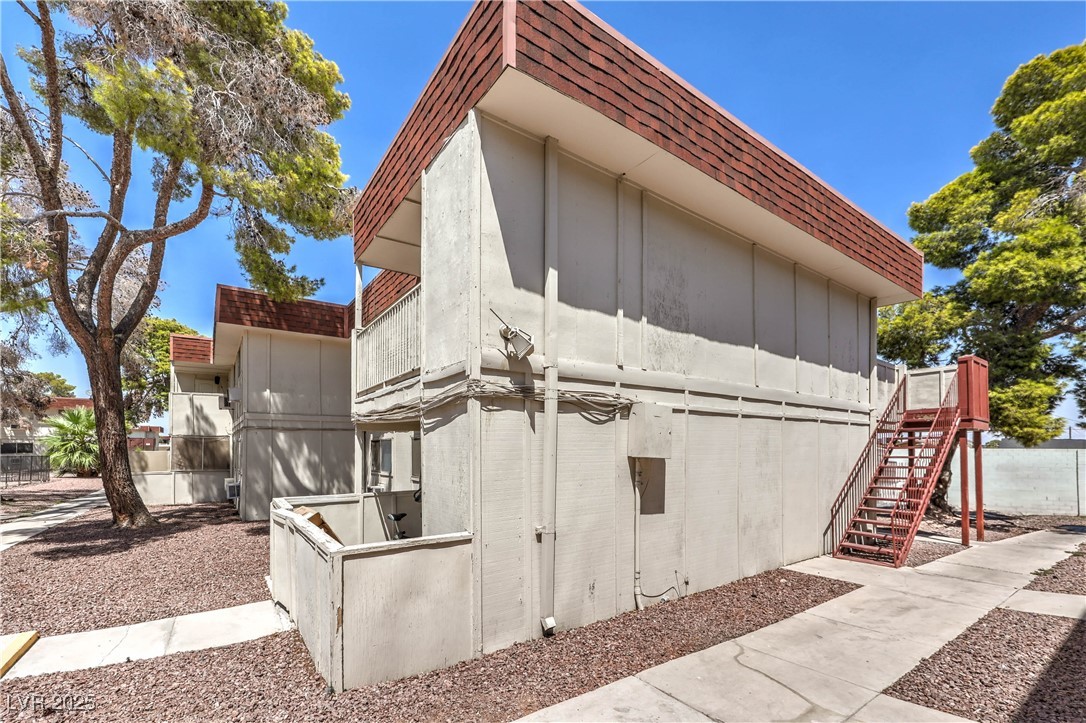 5404 South Swenson Street, Unit 34 Las Vegas, NV 89119 - Photo 27 of 28 View of side of property featuring roof with shingles, stairs, board and batten siding, and mansard roof