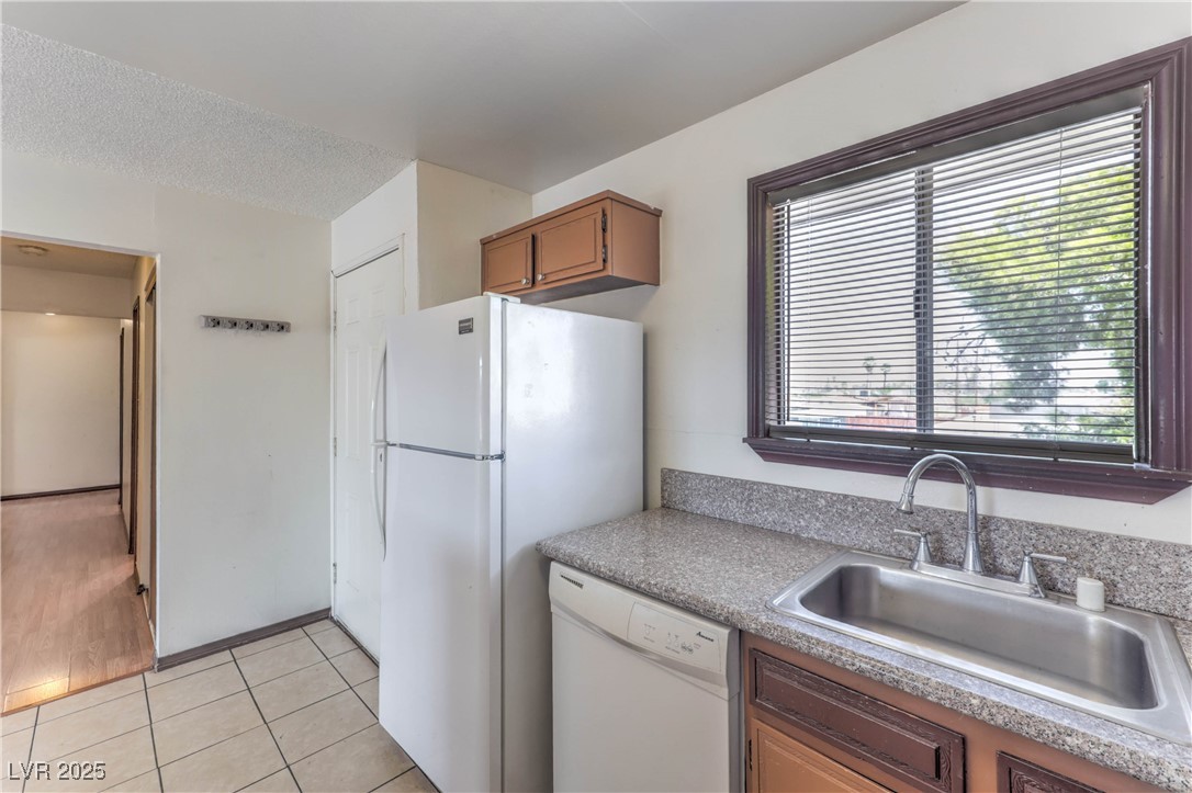 5404 South Swenson Street, Unit 34 Las Vegas, NV 89119 - Photo 6 of 28 Kitchen with white appliances, light tile patterned floors, brown cabinets, light countertops, and a textured ceiling