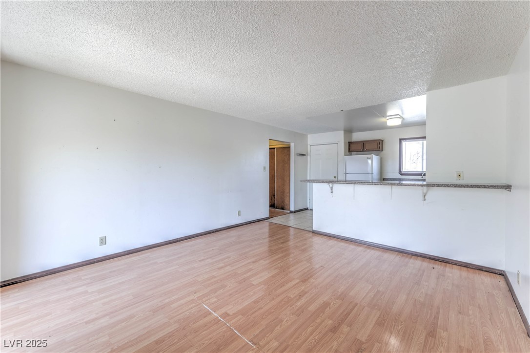 5404 South Swenson Street, Unit 34 Las Vegas, NV 89119 - Photo 9 of 28 Unfurnished living room with light wood-type flooring and a textured ceiling