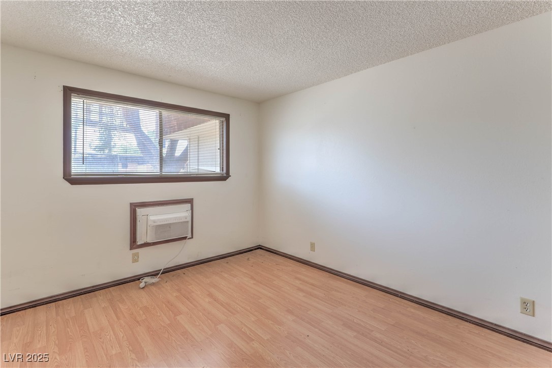 5404 South Swenson Street, Unit 34 Las Vegas, NV 89119 - Photo 10 of 28 Empty room with light wood-type flooring, a textured ceiling, and a wall unit AC