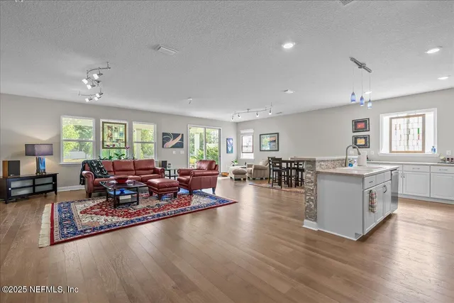 a living room with furniture large window and wooden floor