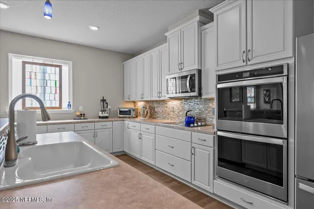 a kitchen with stainless steel appliances granite countertop a stove and white cabinets