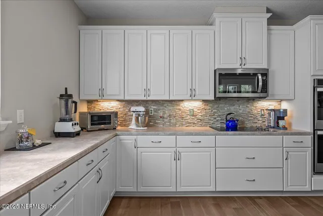 a kitchen with granite countertop white cabinets and stainless steel appliances