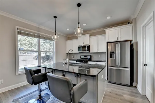 a kitchen with stainless steel appliances granite countertop a refrigerator a stove a sink dishwasher and a dining table with wooden floor