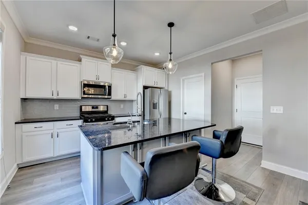 a kitchen with stainless steel appliances kitchen island granite countertop a stove a sink dishwasher a refrigerator and microwave with wooden floor