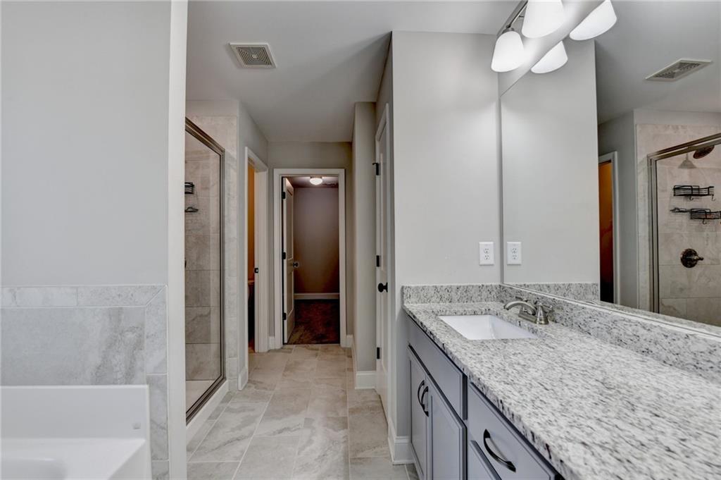 619 Garner Street Buford, GA 30518 - Photo 35 of 45 a bathroom with a granite countertop sink a mirror and a bathtub