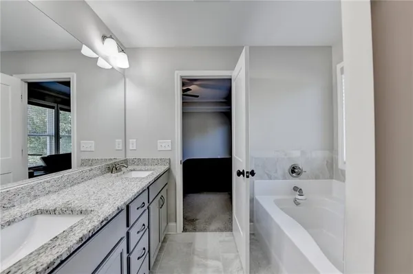 a bathroom with a granite countertop sink a bathtub a mirror and vanity