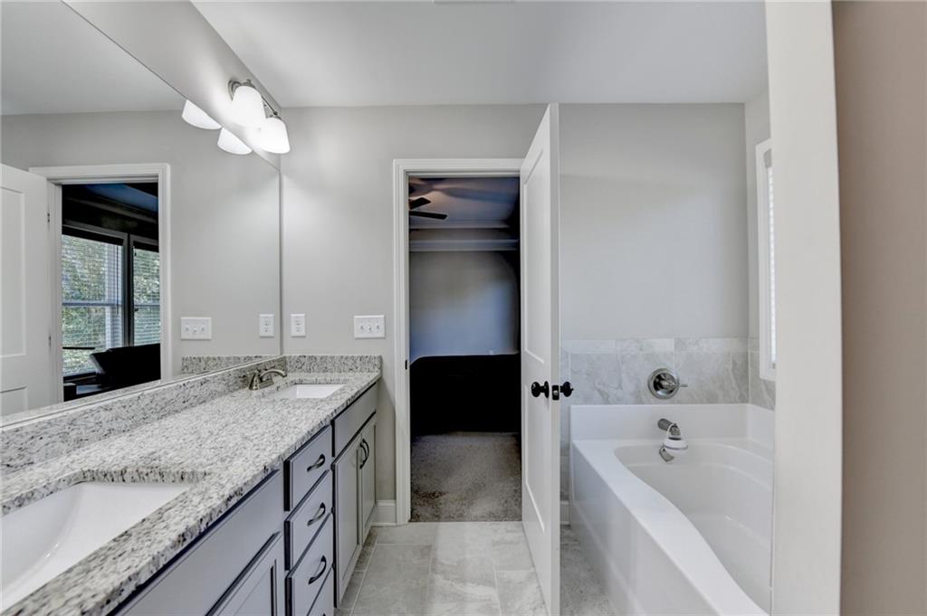 619 Garner Street Buford, GA 30518 - Photo 36 of 45 a bathroom with a granite countertop sink a bathtub a mirror and vanity