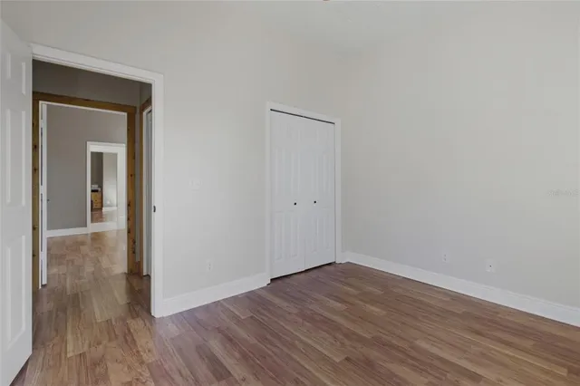 a view of an empty room with wooden floor and closet
