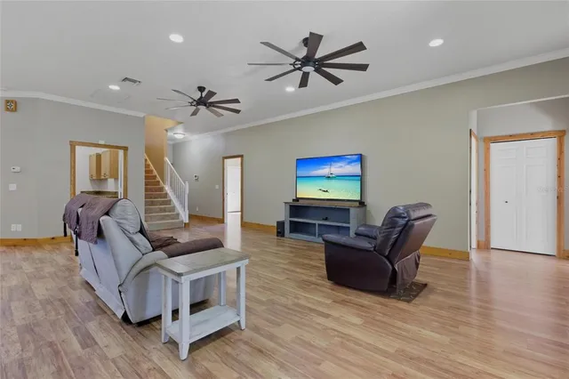 a living room with furniture kitchen view and a wooden floor