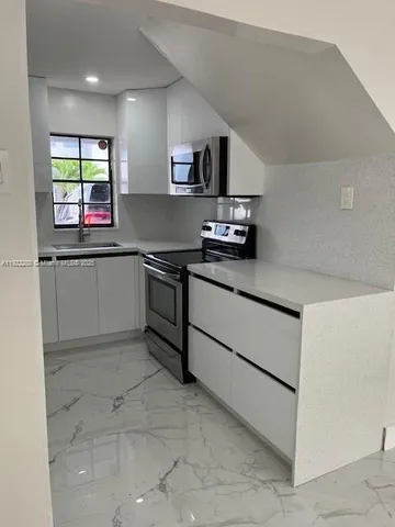 a kitchen with stainless steel appliances granite countertop a sink and a stove