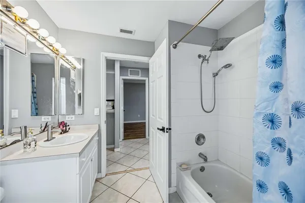 a bathroom with a tub sink double vanity and shower