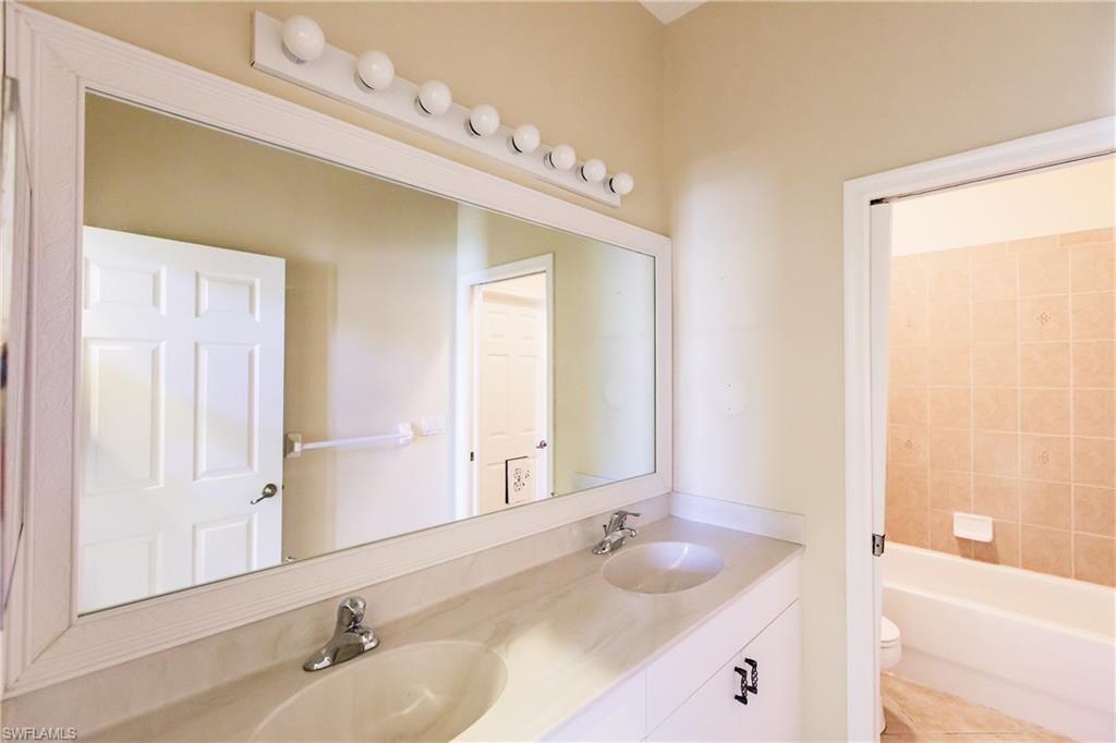 7868 Founders Circle Naples, FL 34104 - Photo 14 of 28 a bathroom with a sink vanity granite tub shower and a mirror