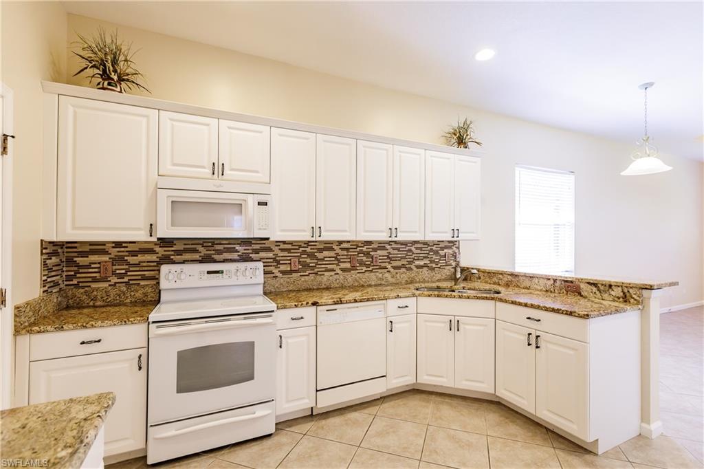 7868 Founders Circle Naples, FL 34104 - Photo 21 of 28 a kitchen with granite countertop white cabinets and white appliances