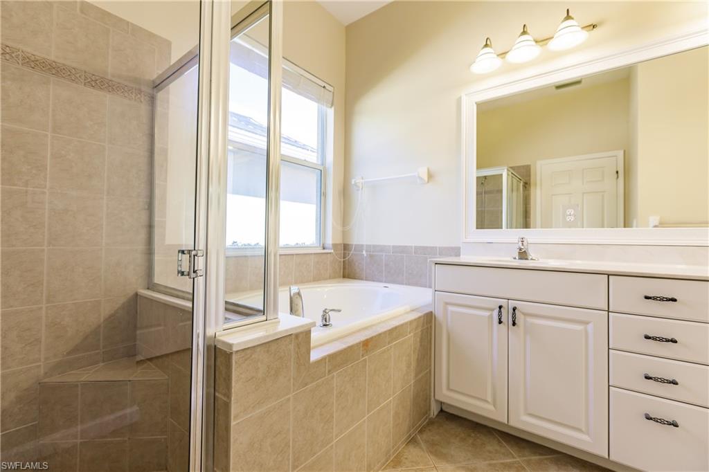 7868 Founders Circle Naples, FL 34104 - Photo 4 of 28 a bathroom with a tub sink and mirror