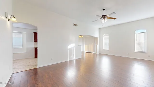 a view of an empty room with wooden floor and a ceiling fan